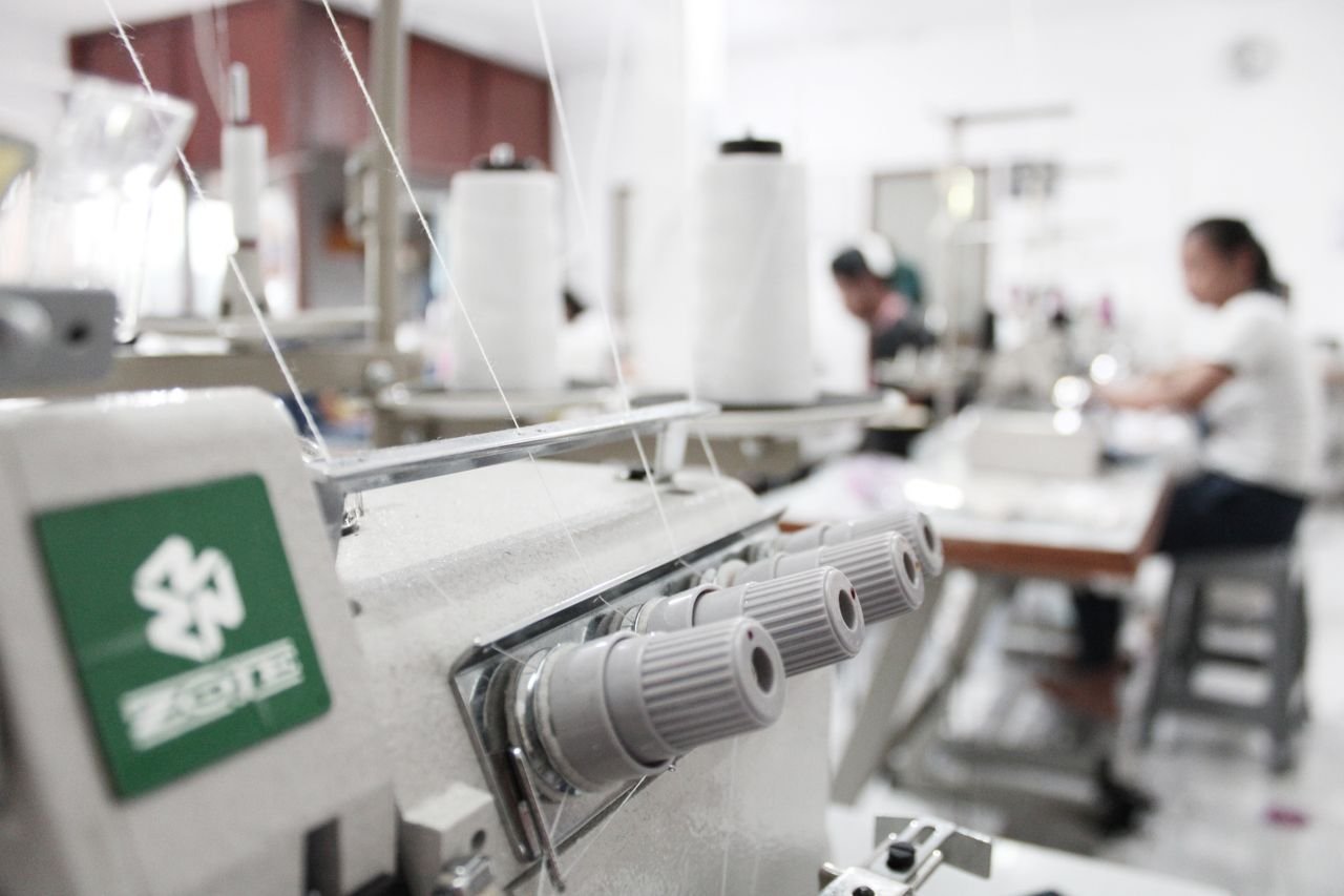 Detailed view of sewing machines in an Indonesian textile workshop, focusing on threads and machinery.